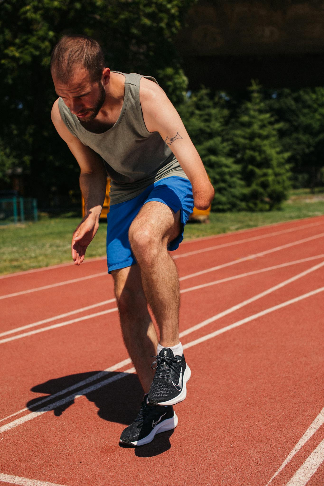 A determined athlete with a prosthetic leg focuses while running on an outdoor track.