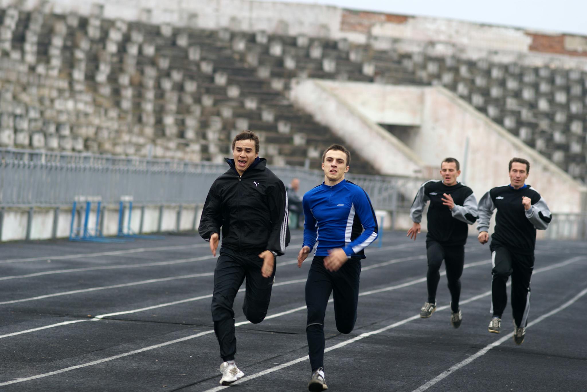 Group of athletes sprinting on an outdoor track, showcasing motion and competition.