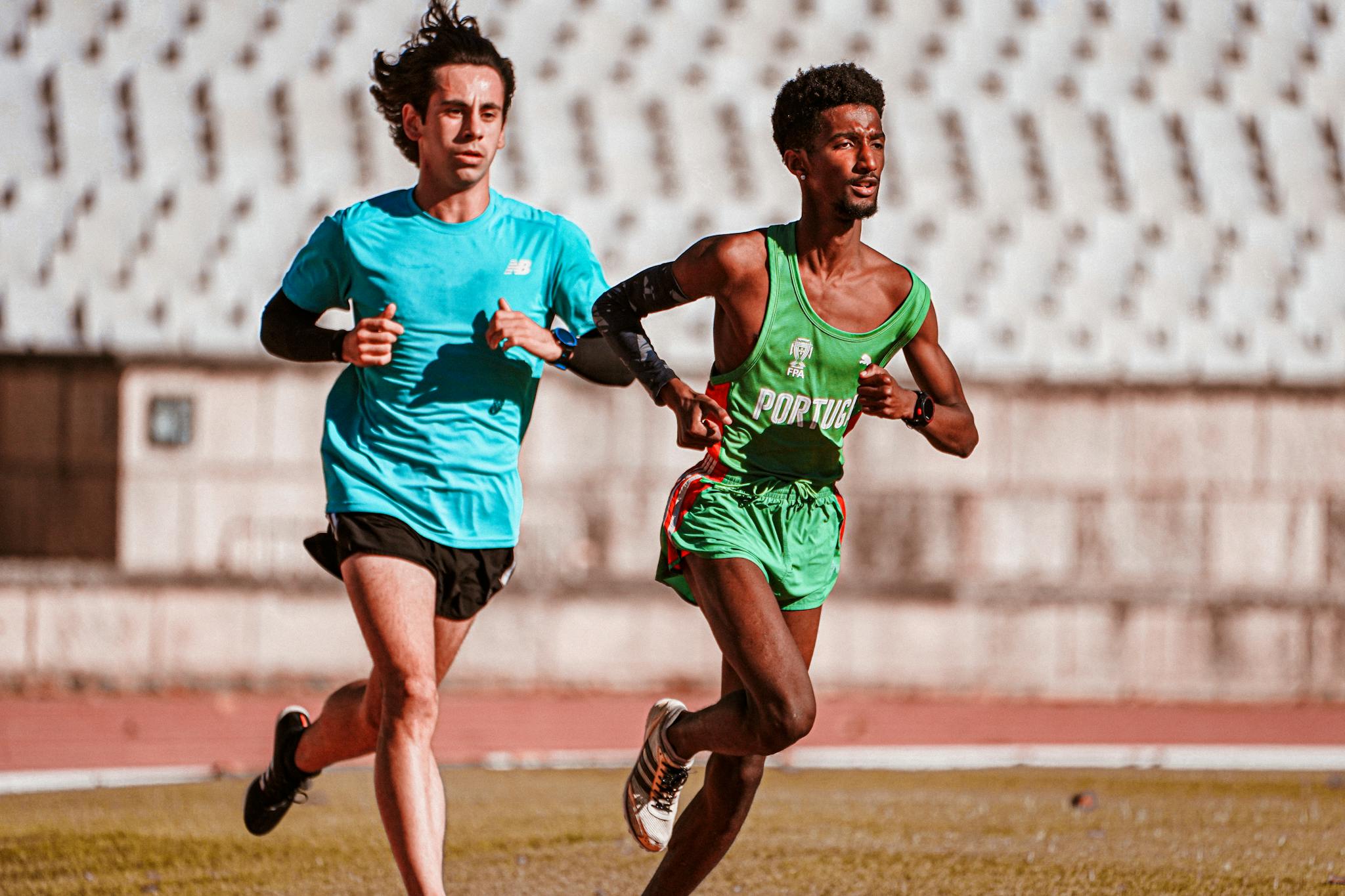 Two male athletes training on an outdoor track, focusing on running and fitness.